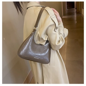 Close-up of brown crescent underarm bag with vintage pleat texture on beige trench coat