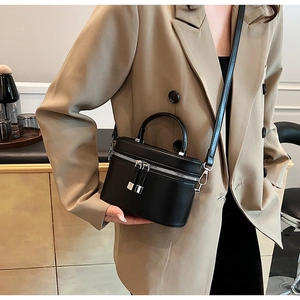 Détail d'un mini sac seau en cuir noir avec zips argentés porté par un mannequin