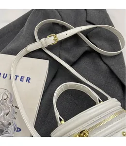 Detailed shot of white mini bucket bag with gold hardware on a grey blazer