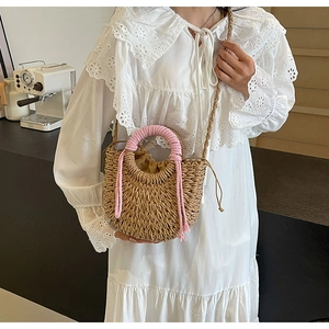 Detail of woven straw bag with pink handles and drawstring closure on a white dress