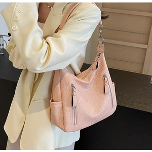 Détail de la texture cuir plissé rose et des multiples poches zippées sur ce sac cabas