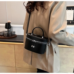 Détail d'un mini sac seau en cuir noir brillant avec garnitures argentées sur un mannequin
