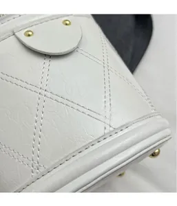 Detail of white quilted leather bucket bag with micro-wrinkle texture and gold rivets