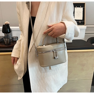 Vue latérale d'un sac seau cylindrique marron clair avec une double fermeture éclair