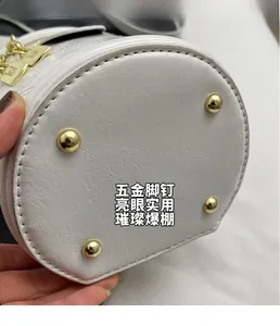 Detail shot of white bucket bag bottom with gold protective studs and pebble texture
