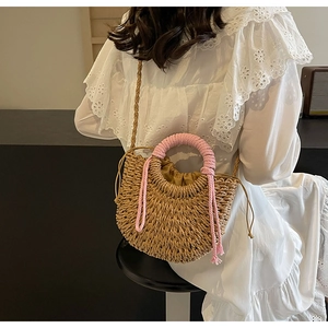 Detail of woven straw bag with pink tassel and drawstring liner on white dress