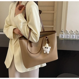 Fashionable khaki leather tote bag with monster charm shown on model in studio