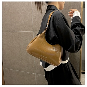 Detail of caramel hobo bag featuring glossy crinkled leather and silver logo lettering