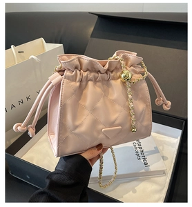 Close-up of pink quilted bucket bag with golden chain strap and drawstring closure