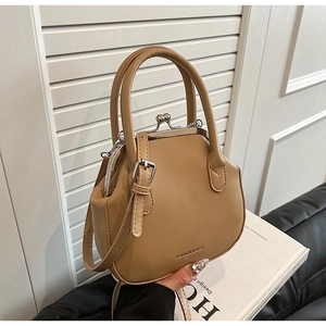 Detailed macro view of khaki retro leather handbag with metallic clasp and handle held by hand