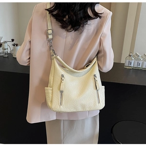 Gros plan du sac hobo vintage crème montrant la texture plissée et la boucle métallique