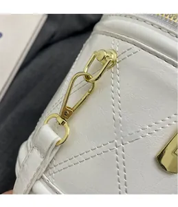 Detailed close-up of gold metal hardware hook on white quilted leather bucket bag