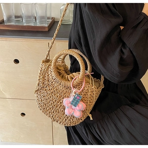 Detailed texture of woven straw bag with pink flower charm and drawstring closure