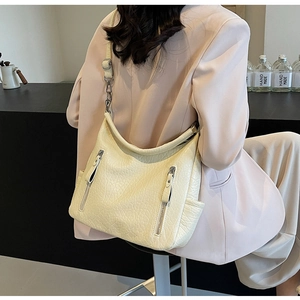 Détail du sac cabas crème avec texture en cuir froissé et fermetures éclair verticales