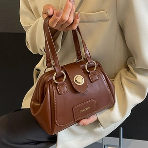 Deep brown Boston shoulder bag with gold hardware and stylish leather handle detail