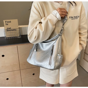 Détail d'un sac Hobo argenté métallisé avec texture en cuir plissé et doubles zips
