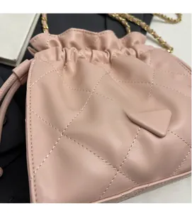 Close-up of pink quilted leather bucket bag featuring drawstring and golden chain strap