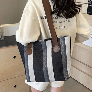 Vertical striped woven tote bag with brown straps shown on shoulder for daily use