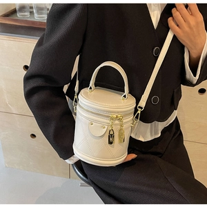 Close-up of white quilted leather bucket bag with gold hardware and double zipper detail