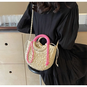 Detail of woven straw bag with pink handles and secure drawstring closure for beach