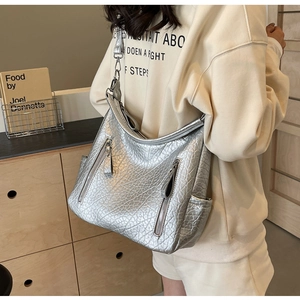 Détail du sac hobo argenté métallisé avec texture peau d'éléphant et poches zippées