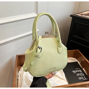 Detail of mint green crossbody bag with kiss-lock closure and dual handles