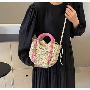 Detail of woven straw bag with magenta handles and drawstring closure on a dress