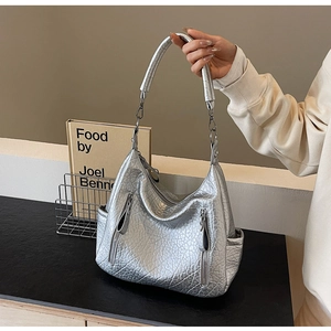 Détail du sac hobo argenté avec plusieurs zips métalliques et une texture PU de qualité