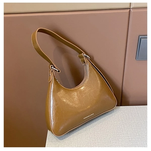 Close-up of brown glossy leather hobo bag with white FASHION & BAG print detail