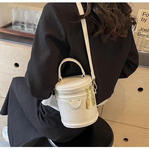 Detail view of white quilted bucket bag with gold lock charms on a fashion model