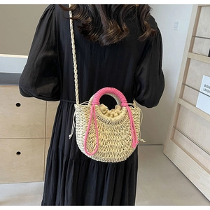 Detail of woven straw bucket bag with pink rope handle and drawstring lining for beach