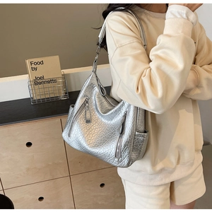 Sac hobo métallisé argenté avec texture craquelée et zips multiples porté à l'épaule