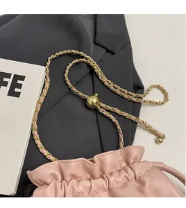 Detailed view of pink quilted bucket bag with gold-tone metal chain strap and ball buckle
