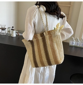 Detail of woven straw tote bag with vertical stripes and tassel trim for summer