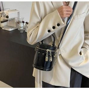 Detail of a black quilted bucket bag with gold lock charms in a stylish cafe setting