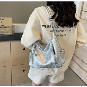 Détail du sac hobo argenté avec poches zippées et finition en similicuir texturé