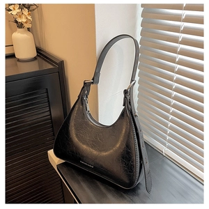 Detail of black glossy cracked leather underarm bag with silver zipper and logo