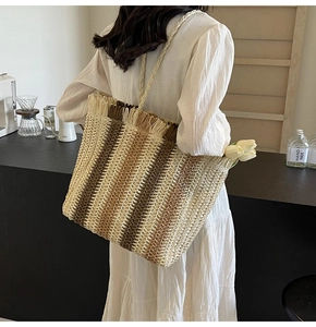 Detail of multi-colored striped straw tote bag with fringe edge and long woven handles