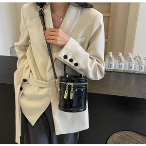 Detail of black glossy leather bucket bag with gold hardware and dual zipper closure