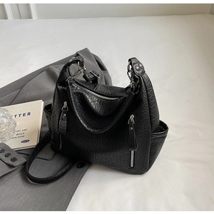 Détail d'un sac cabas en cuir noir texturé avec fermetures éclair argentées et poches latérales