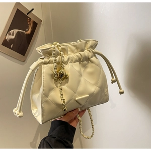 Detail of quilted beige bucket bag with gold chain strap and adjustable metal ball buckle