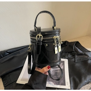 Close-up of black quilted leather bucket bag featuring gold lock zipper and dual handles
