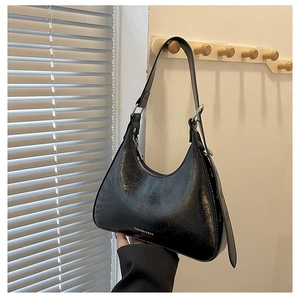 Close-up of black crescent underarm bag with oily wax leather texture and silver zipper