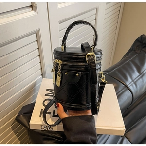 Close-up of black quilted bucket bag featuring a glossy finish and gold metal hardware
