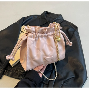 Macro detail of pink quilted bucket bag with golden chain and metallic ball charm