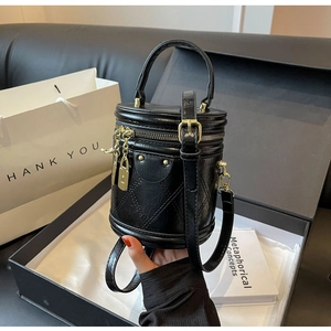 Detail of a black quilted leather bucket bag with gold hardware in a gift box setup