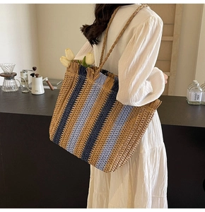 Detail of hand-woven straw tote bag with striped pattern and rustic fringe edges