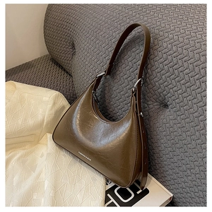 Detail view of brown faux leather baguette bag with fashion lettering on knit background