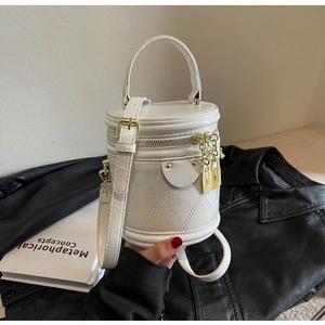 Detail of white quilted cylinder bag with gold lock hardware and top handle strap