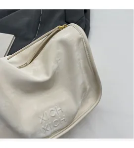Détail du sac Boston blanc crème avec texte XICH XICH en relief et zip métallique
